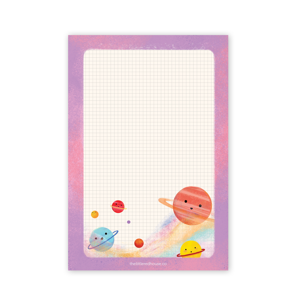 Grid Stardust Notepad. Pink and pale purple bordered notepad features illustration of happy planets floating in a hazy colorful outer space. Features a grid for lists, notes, and doodles.